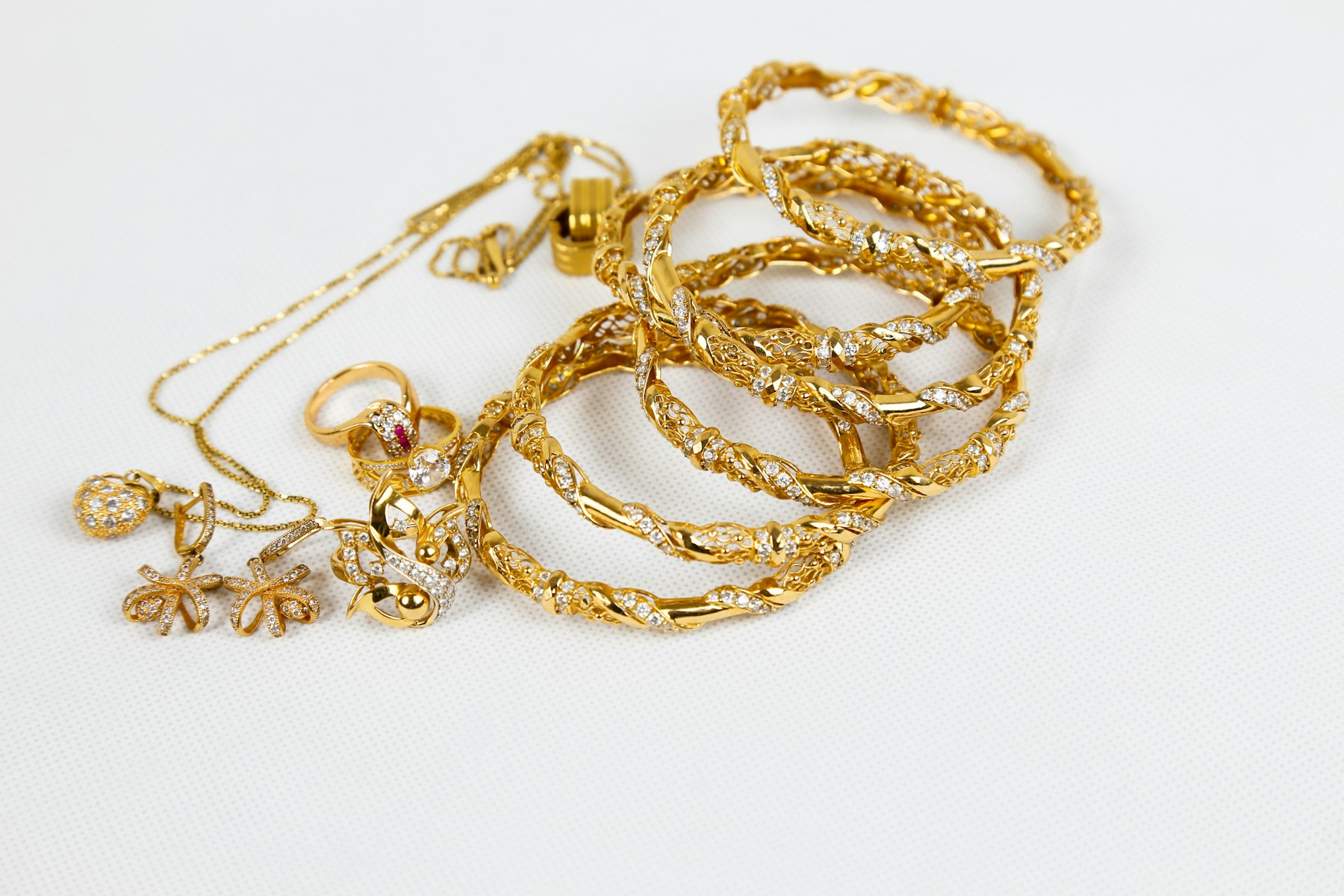 Gouden kettingen, armbanden en ringen op een lichte ondergrond